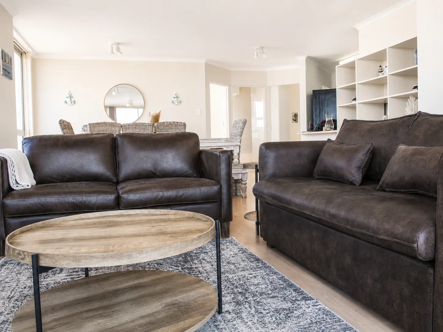 Comfortable living room with brown leather sofas, a round wooden coffee table and dining area
