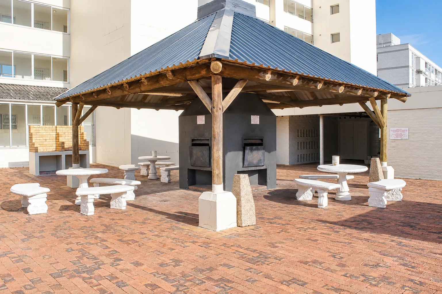 Covered communal braai area with built-in grills and outdoor concrete tables and benches