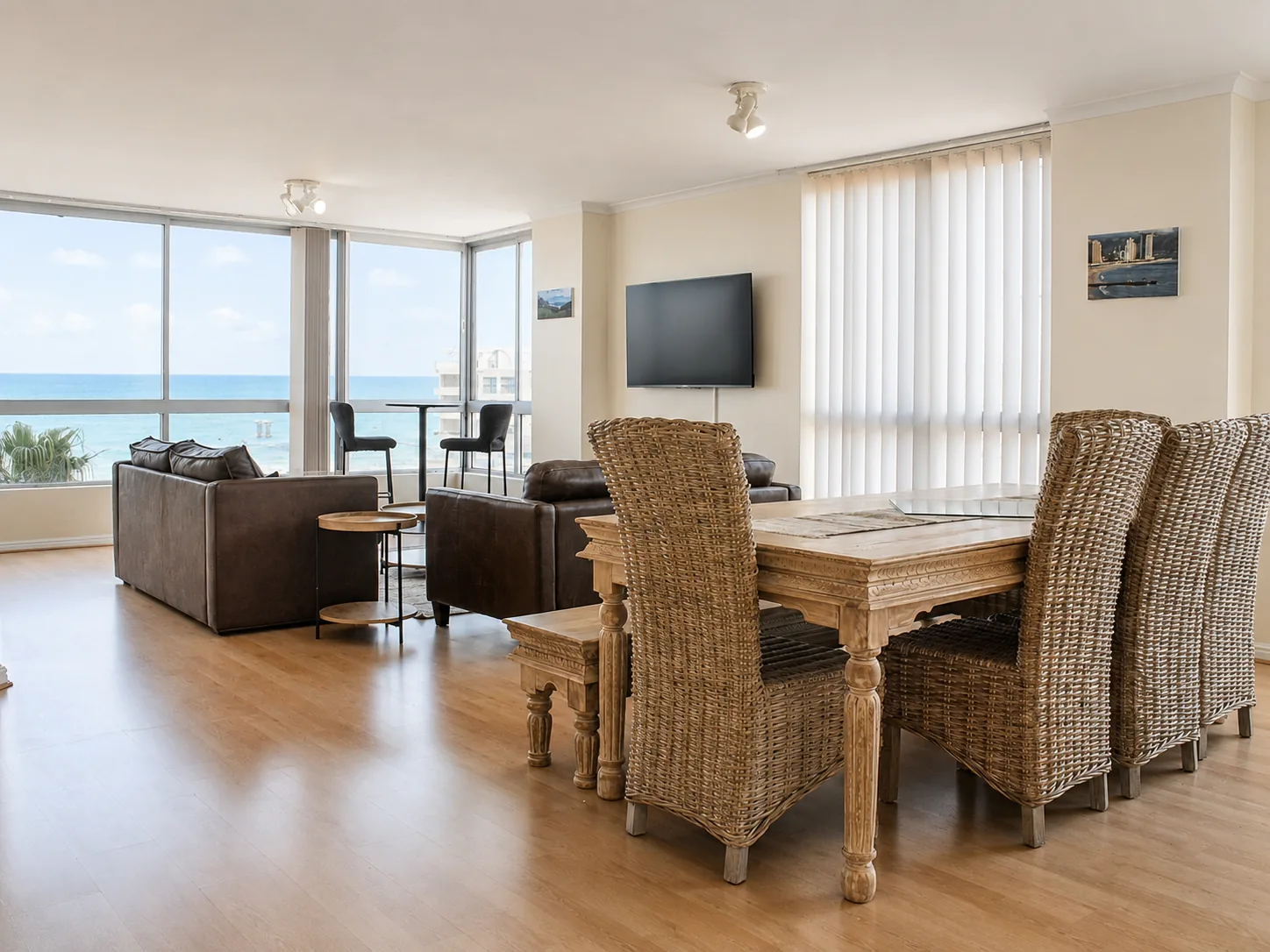 Bright apartment living room with leather sofas, television and large windows overlooking the ocean