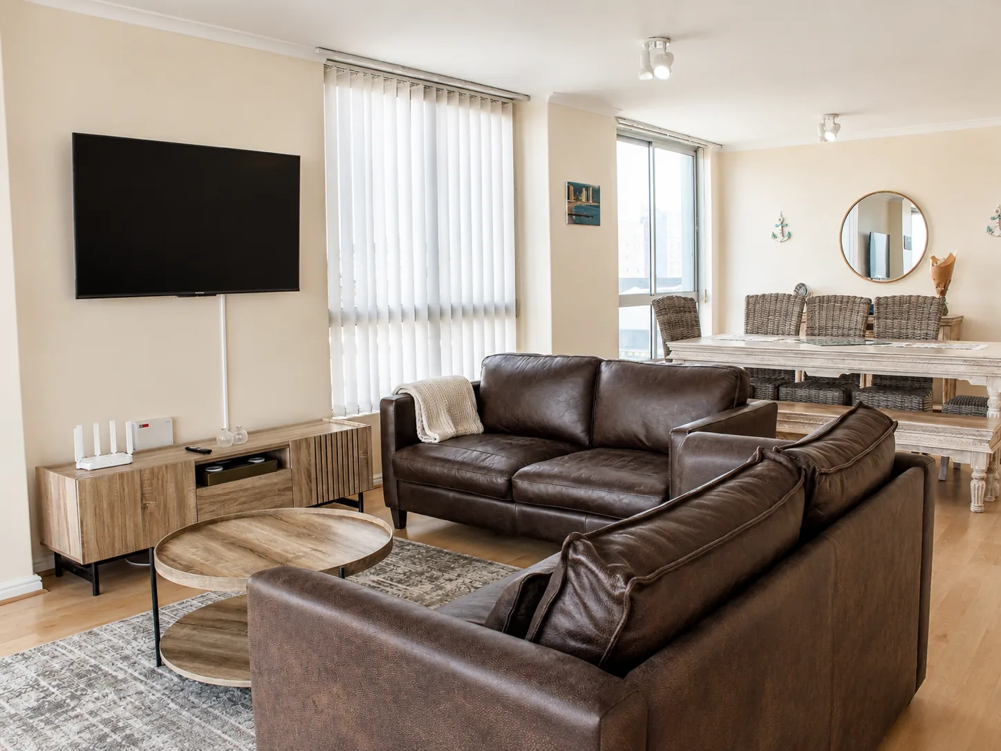 Spacious open-plan living and dining room with leather sofas, wooden furniture and wicker dining chairs