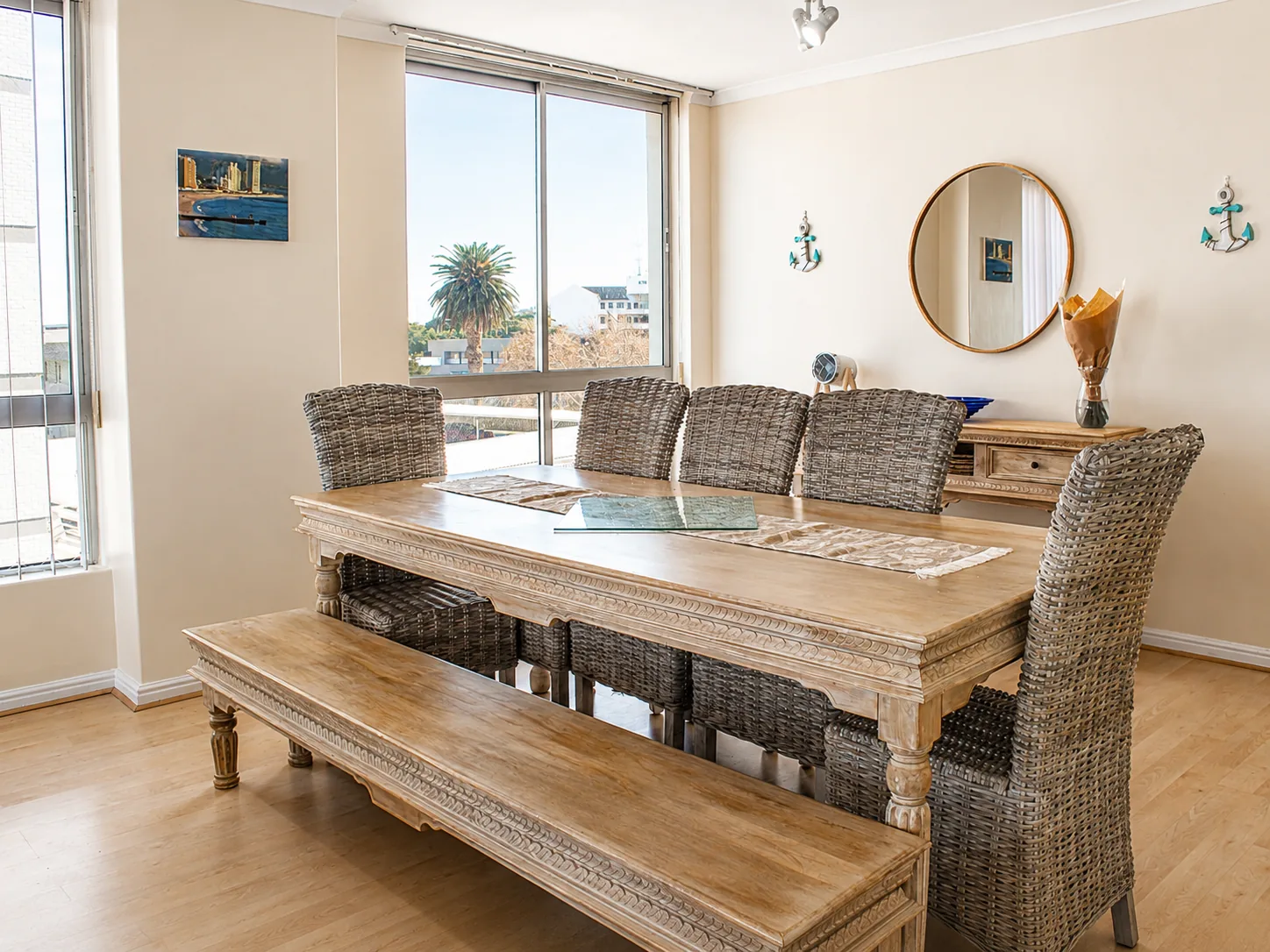 Wooden dining table with bench and wicker chairs in a bright apartment dining area